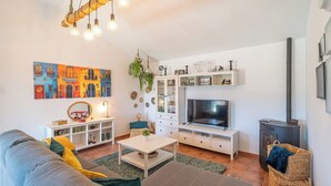 A living room with a sofa, TV, white cabinets, and a fireplace. - El Rincón de Esther Cómpeta by Ruralidays (Málaga)