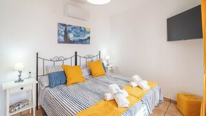 A neatly arranged bedroom with a bed, bedside tables, a painting, and a television. - El Rincón de Esther Cómpeta by Ruralidays (Málaga)
