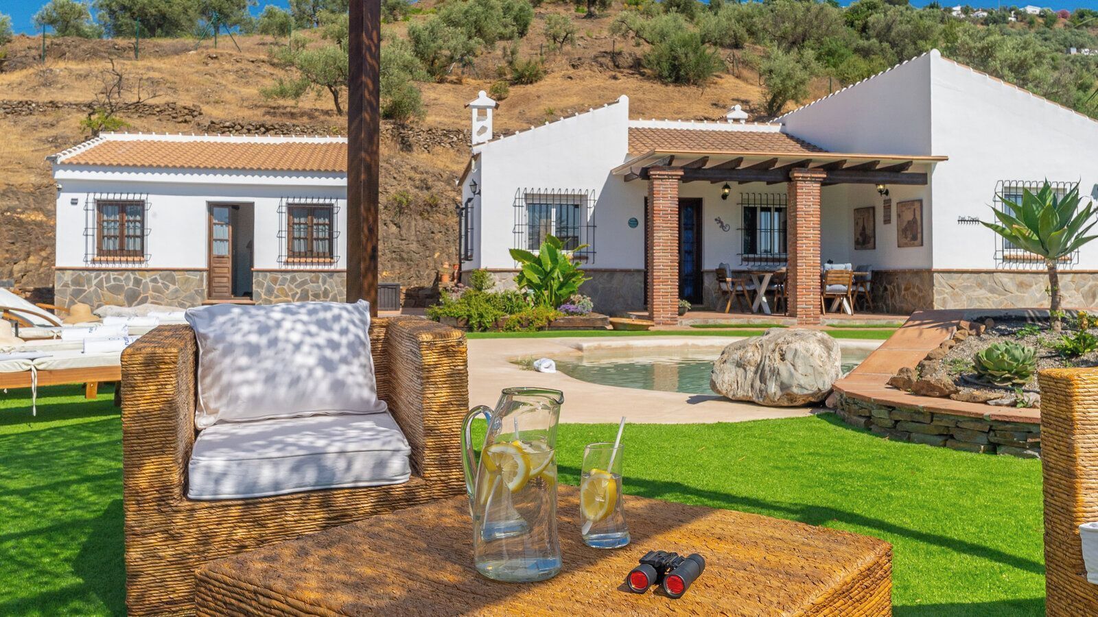 Una villa con piscina, mobiliario exterior y jardín bien cuidado.