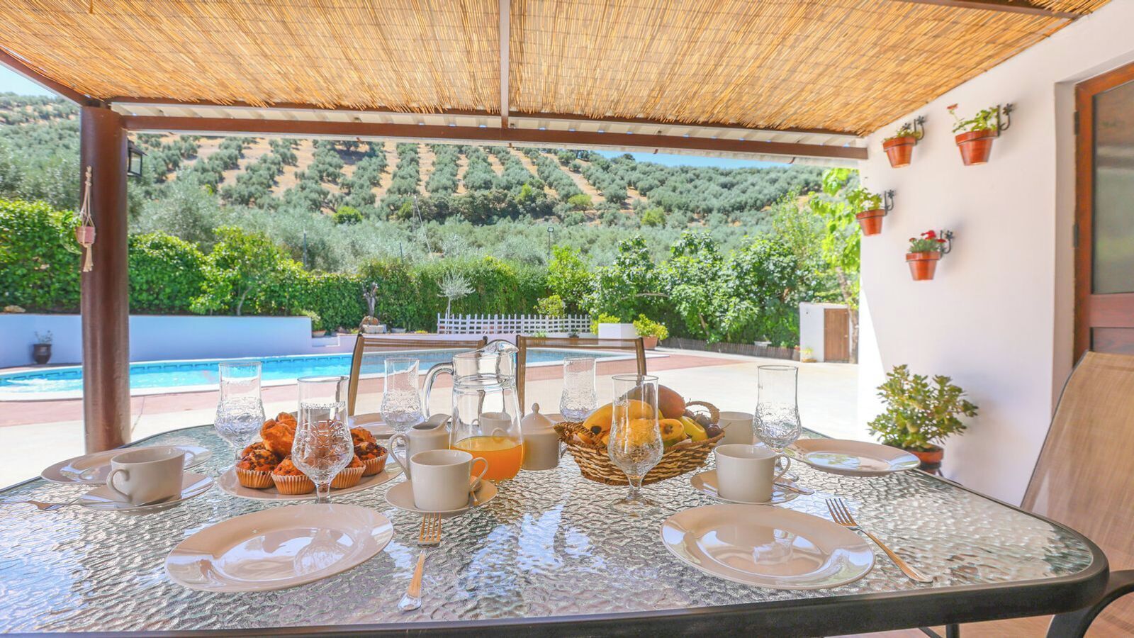 A table set for breakfast with a view of a pool and greenery.
