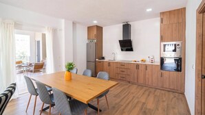 A modern kitchen with wooden cabinets, a built-in oven, and a dining area with a wooden table and chairs. - Puerta del Sol Olvera by Ruralidays (Cádiz)