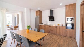 Eine moderne Küche mit Holzschränken, einem eingebauten Ofen und einem Essbereich mit einem Holztisch und Stühlen.