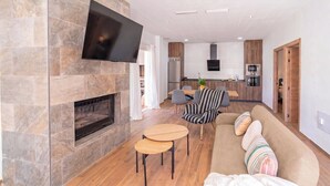 A modern living room with a fireplace, a flat-screen TV, a sofa, and a dining area with chairs. - Puerta del Sol Olvera by Ruralidays (Cádiz)