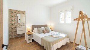 A bedroom with a bed, bedside lamps, a wooden floor, a stone wall, a window, and a wooden hanger. - Puerta Encina Olvera by Ruralidays (Cádiz)