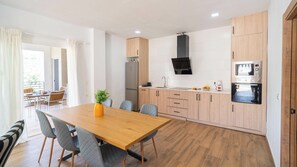 A modern kitchen with wooden cabinets, a central island, and a dining area with a table and chairs.