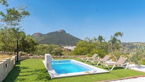 A swimming pool with a view of mountains, surrounded by grass and lounge chairs. - Alma de Olivo El Gastor by Ruralidays (Cádiz)