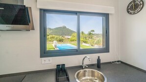 A kitchen with a large window, a stainless steel sink, and a black countertop. - Alma de Olivo El Gastor by Ruralidays (Cádiz)