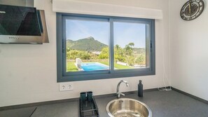 A kitchen with a large window, a stainless steel sink, and a black countertop. - Alma de Olivo El Gastor by Ruralidays (Cádiz)