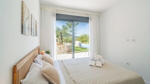 A bedroom with a bed, a window with curtains, and a view of a pool and greenery. - Alma de Olivo El Gastor by Ruralidays (Cádiz)