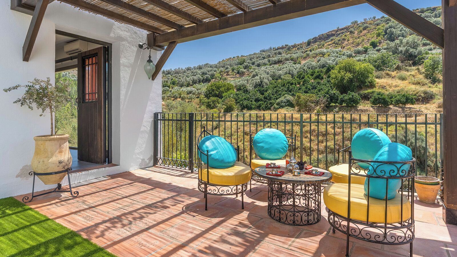 A patio with outdoor furniture, a table, and a view of a hillside.