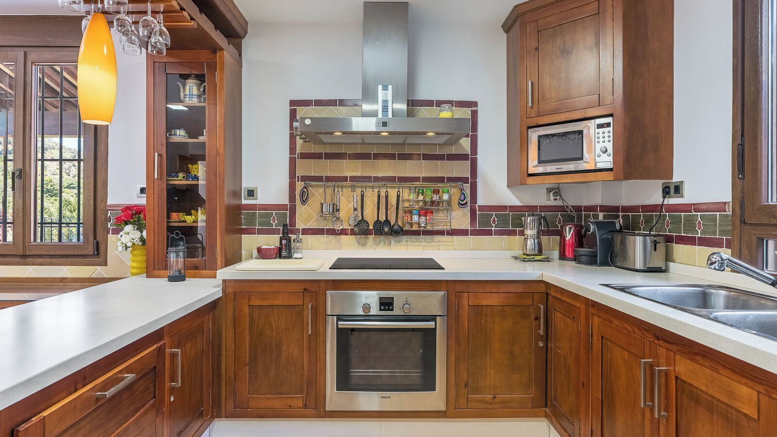 A modern kitchen with wooden cabinets, a stainless steel oven, a microwave, and a variety of kitchen utensils.