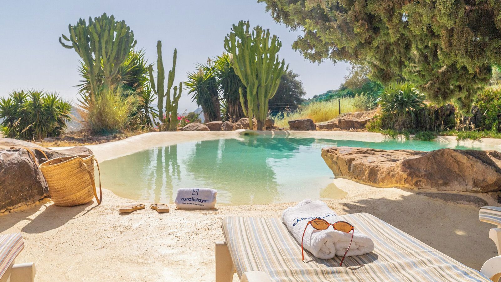 Zona de piscina con sillas de descanso, una toalla y un bolso.