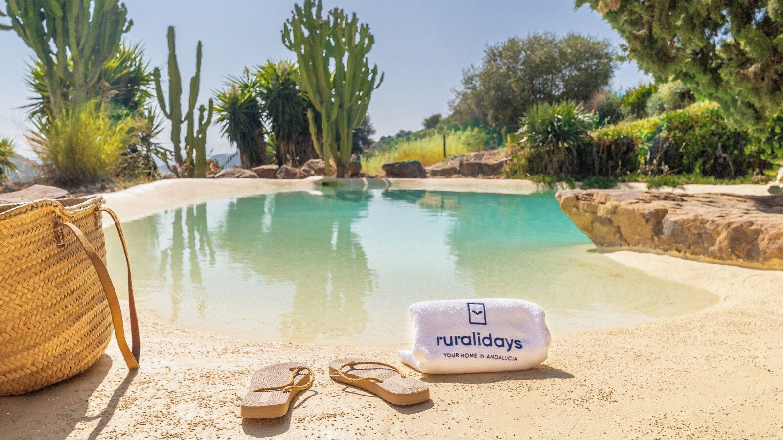 A poolside area with a towel, flip-flops, and a woven bag.