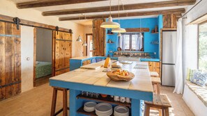 Eine Küche mit blauer Arbeitsplatte, Holzschränken und einer zentralen Kochinsel mit einer Schüssel Obst.