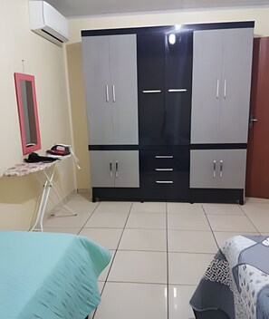 A bedroom with a bed, a wardrobe, an ironing board, and a mirror. - Sobrado 02quartos prox Recanto Cataratas (Foz do Iguaçu)