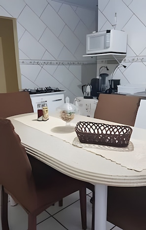 A kitchen with a dining table, chairs, a microwave, and a gas stove. - Sobrado 02quartos prox Recanto Cataratas (Foz do Iguaçu)