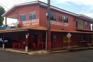 A two-story building with the name 'Mercado' on the facade, featuring a covered entrance with red chairs outside. - Sobrado 02quartos prox Recanto Cataratas (Foz do Iguaçu)