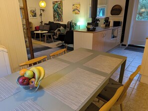 Ein Essbereich mit einem Tisch für zwei Personen, einer Obstschale und einer Küche im Hintergrund.
