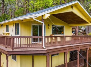 Ein gelbes Haus mit einer Holzterrasse und einer überdachten Veranda.