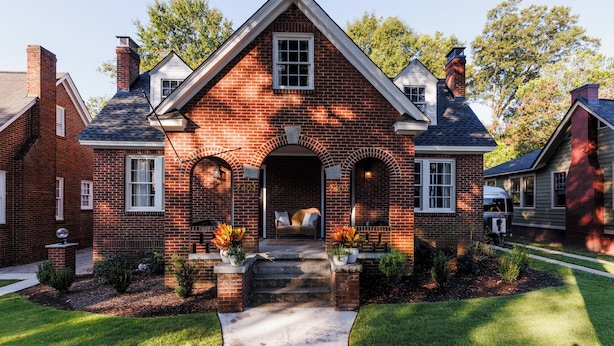 A brick house with a front porch, a chimney, and a mailbox.