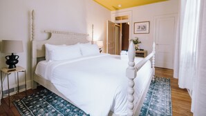 Ein Schlafzimmer mit einem Bett, einem Deckenventilator, einem Nachttisch, einer Lampe und einem gemusterten Teppich.