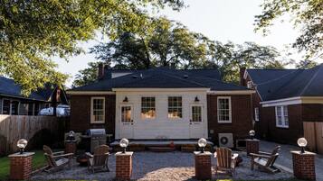 A backyard with a gravel path, brick seating, and a house with a chimney.