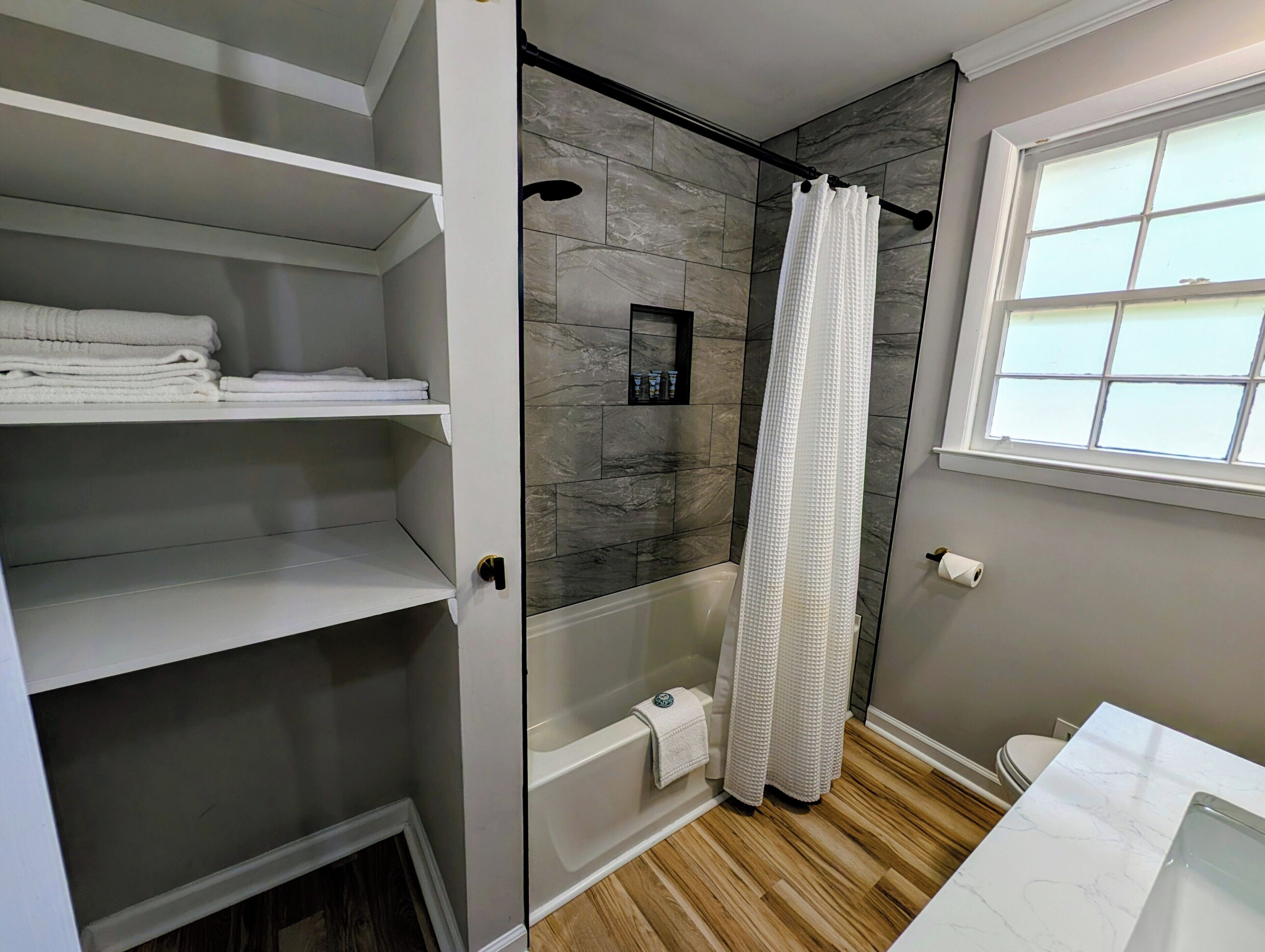 Un baño con ducha, inodoro y tocador blanco.
