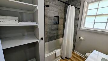 Un baño con ducha, inodoro y tocador blanco.