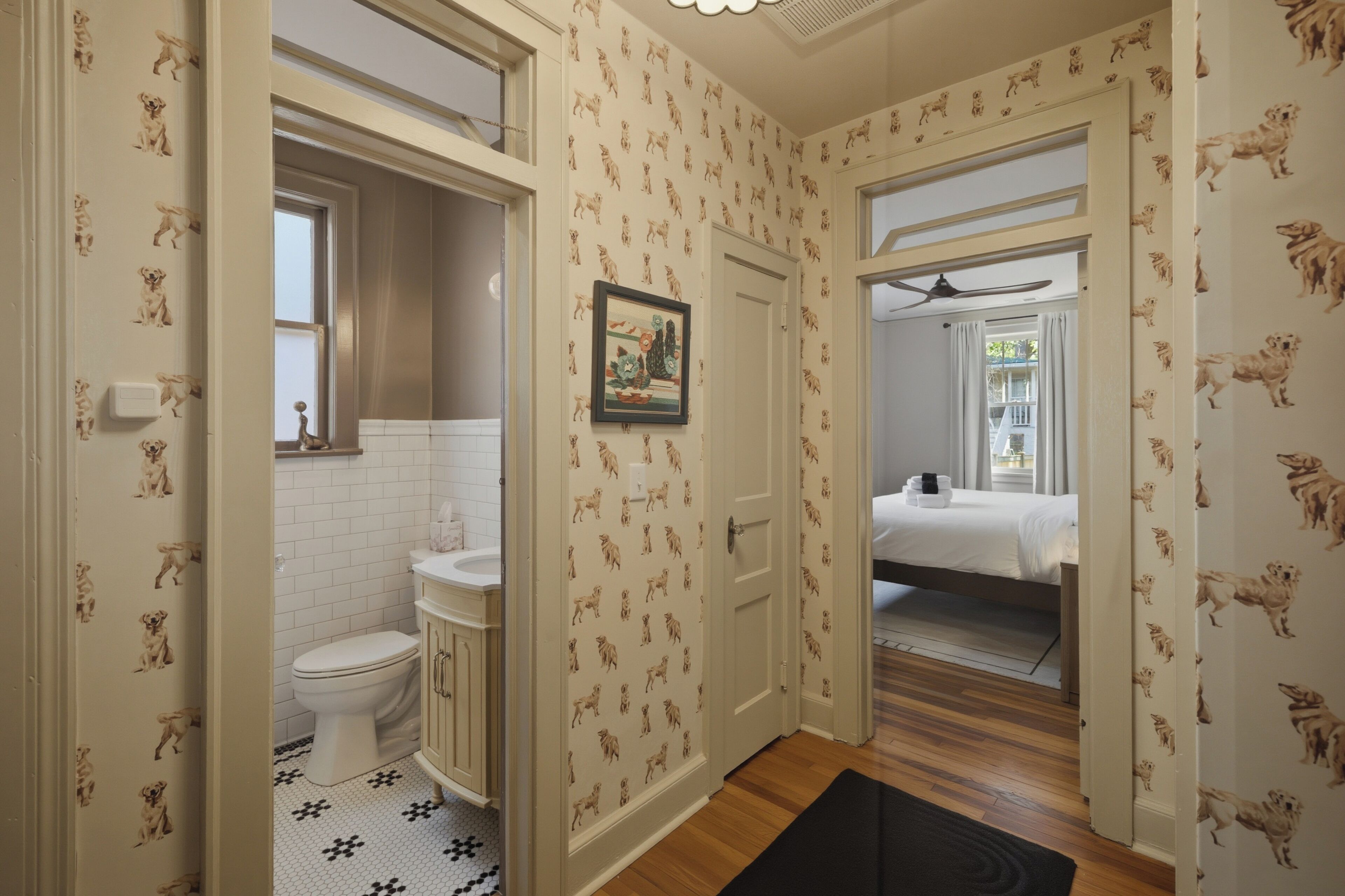 A hallway with a bathroom on the left, a bedroom on the right, and a door leading to another room.