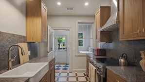 A modern kitchen with wooden cabinets, a white sink, a stove, and a microwave.