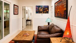 A living room with a brown leather sofa, a wooden coffee table, a patterned rug, and a painting on the wall. -     Peaceful 1BR Cabin Near Malibu • AC • Pet Friendly (Agoura Hills)