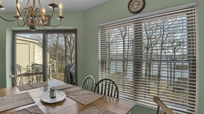 A dining area with a wooden table, chairs, a chandelier, and a window with blinds. - Midlake Retreat Waterfront 3BR Penthouse, Lake Club Included, Pool, Ski & Golf (Lake Harmony)
