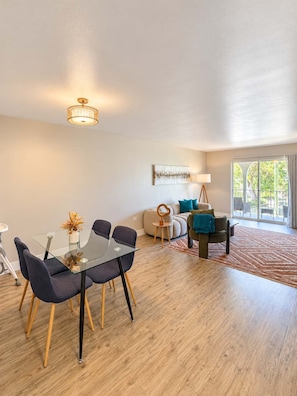 Una sala de estar moderna con una mesa de vidrio, sillas oscuras, un sofá y una mesa de centro.