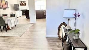 Een ruime woonkamer met een eettafel, stoelen, een bank en een salontafel.