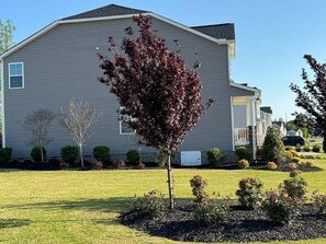 A single-story house with a front yard, a lawn, and a tree with red leaves. - Spacious new house in Mebane, NC (Mebane)