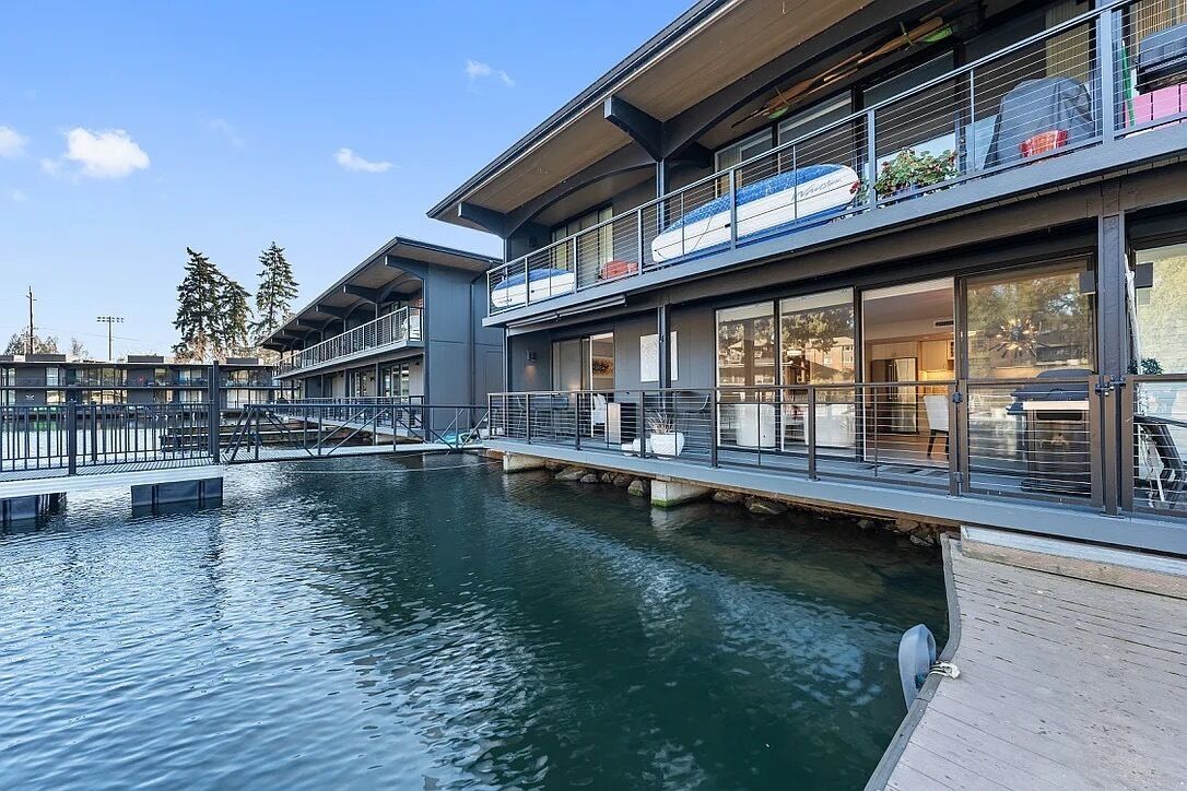Een modern gebouw met een waterkanaal, een overdekte gangpad en een balkon met zitplaatsen.