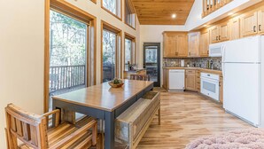 Un'ampia cucina con mobili in legno, un'isola grande e vista sull'esterno attraverso diverse finestre.