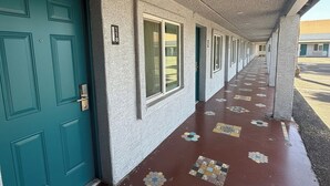 Un pasillo con puertas color turquesa, letreros numerados y baldosas de diseño.