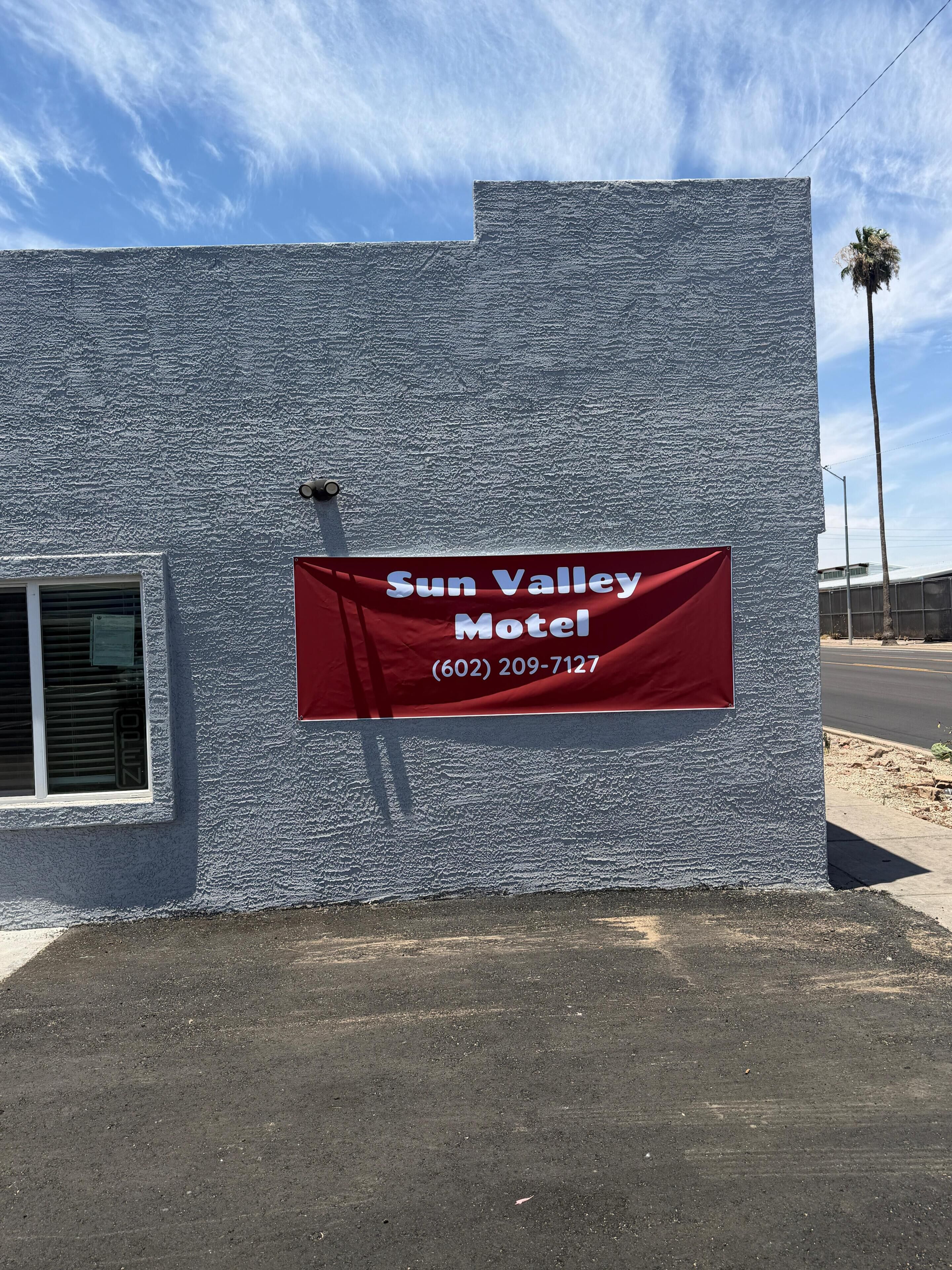 A building with a red banner advertising the Sun Valley Motel and a phone number.