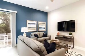 Ein modernes Wohnzimmer mit einer Couch, einem Couchtisch, einem Fernseher und Kunstwerken an der Wand.