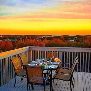 Eine Terrasse mit Tisch für vier Personen, mit Blick auf eine Landschaft aus Bäumen und Gebäuden.
