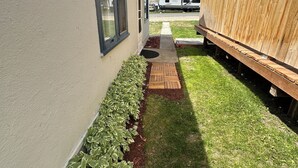 Una propiedad residencial con un camino pavimentado, una terraza de madera y un patio cercado.