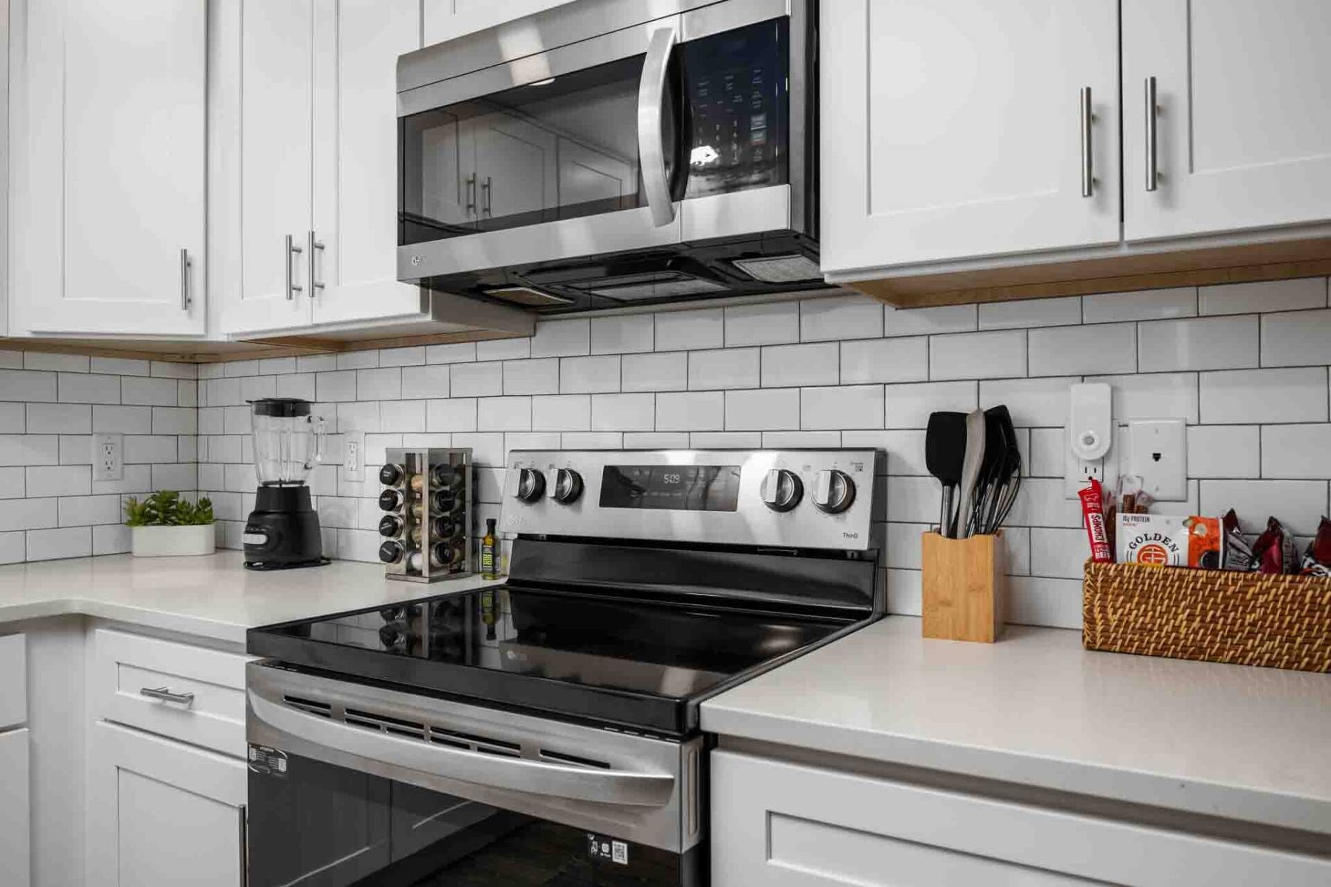 A kitchen with white cabinets, a stainless steel stove, a microwave, and a coffee maker.
