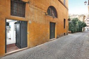 Eine enge Kopfsteinpflasterstraße mit einem Gebäude, das eine schwarze Tür und ein Fenster mit einem Metallgitter hat.