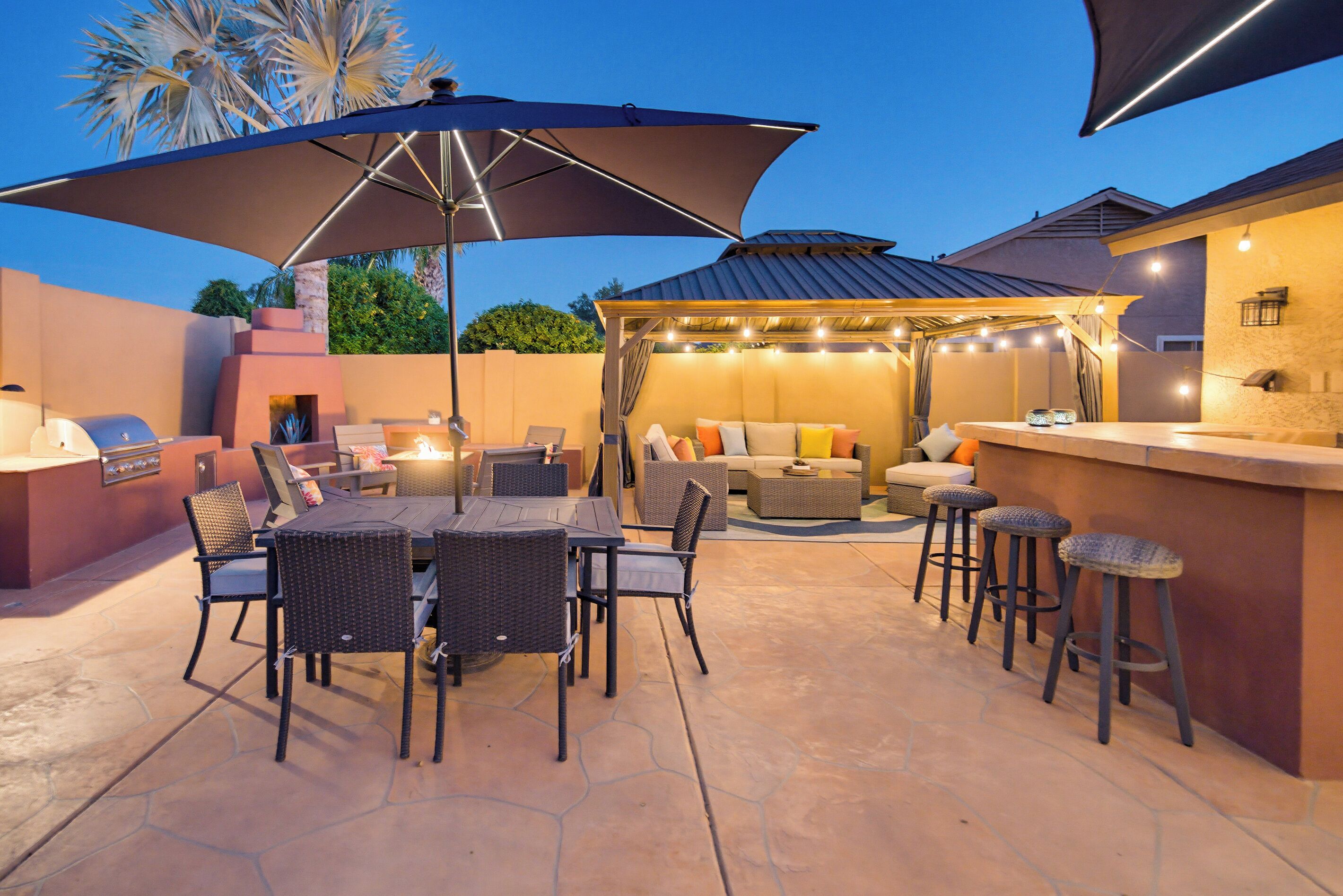 An outdoor patio with a dining table, chairs, and a bar area.