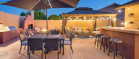 An outdoor patio with a dining table, chairs, and a bar area.