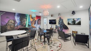 Ein modernes Zimmer mit einem runden Tisch, Stühlen, einem Flachbildfernseher und Kunstwerken zum Thema Star Wars.
