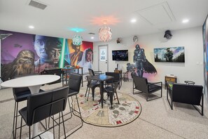 Ein modernes Zimmer mit einem runden Tisch, Stühlen, einem Flachbildfernseher und Kunstwerken zum Thema Star Wars.