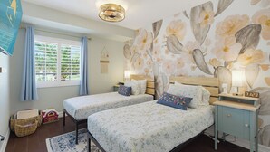 Ein Schlafzimmer mit zwei Betten, einem Fenster mit Rollläden, einer Wanduhr und einer Wanddekoration.