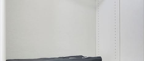 A storage closet with shelves, a hanging rack, and a suitcase labeled 'GRACO.'